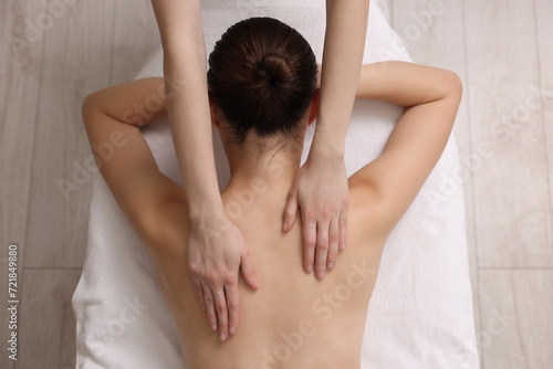 Woman receiving back massage on couch in spa salon, top view