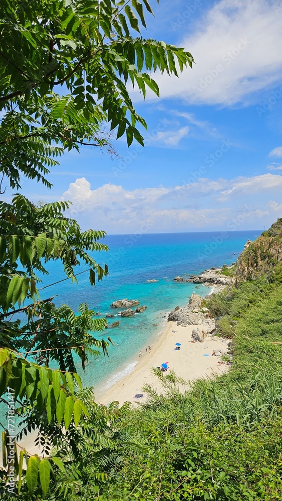 Embark on a visual journey to Calabria's enchanting beach, where golden sands meet the azure sea in perfect harmony. Crystal-clear waters invite you to immerse yourself in a summer haven.