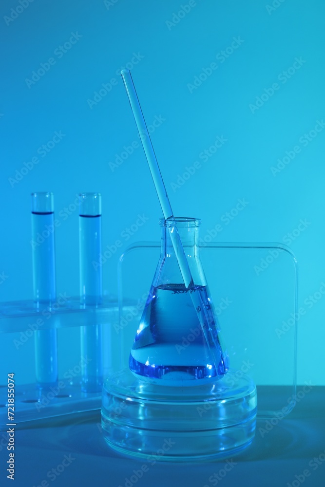 Laboratory analysis. Different glassware on table against blue background Laboratory analysis. Different glassware on table against blue background
