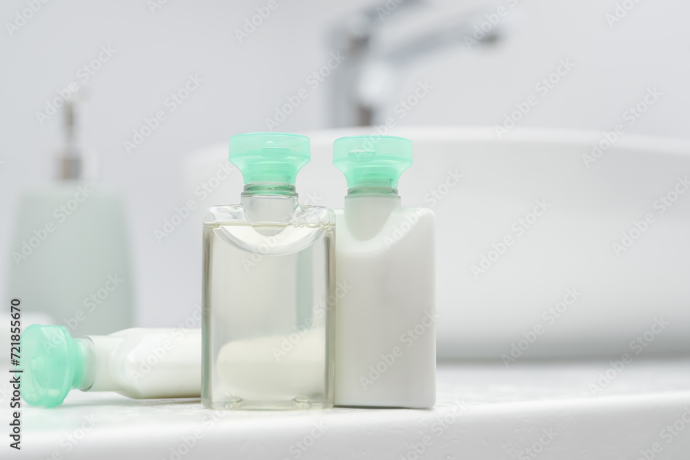 Mini bottles of cosmetic products on white countertop in bathroom. Space for text Mini bottles of cosmetic products on white countertop in bathroom. Space for text