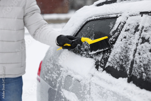 Man cleaning snow from car outdoors, closeup