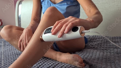Young woman does photoepilation of legs at home. Laser hair removal of beautiful sexy legs photo