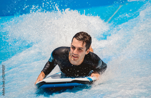 Young man surfing on a wave simulator at a water amusement park © romaset
