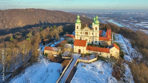 Camaldolese monastery and baroque church in the wood on the hill in Bielany, Krakow, Poland , Aerial 4K video in sunset light in winter. Far view of Vistula River and Cracow city in the background photo
