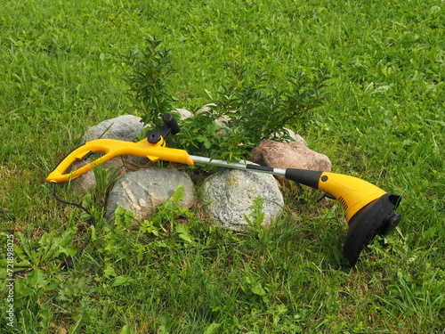 Yellow corded electrical grass trimmer. Lightweight string brushcutter for cutting grass. Tools for edging and cutting domestic lawns photo