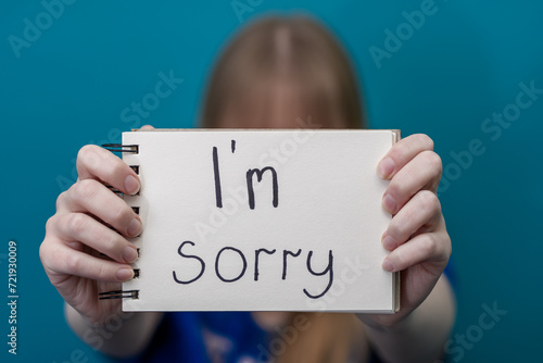 Dziecko trzyma w dłoniach kartkę z napisem przepraszam