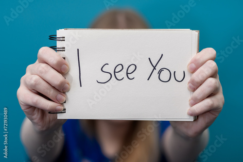 Kobieta trzyma kartkę z napisem widzę cie, wsparcie psychiczne i akceptacja drugiej osoby 