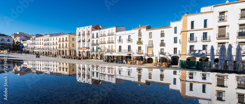 Facades of white houses that are reflected in the water of the city of Caceres, Extremadura. photo