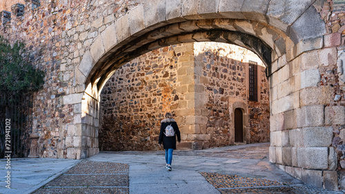 Tourist woman passing through the entrance arch in the wall that gives access to Caceres, Spain. photo