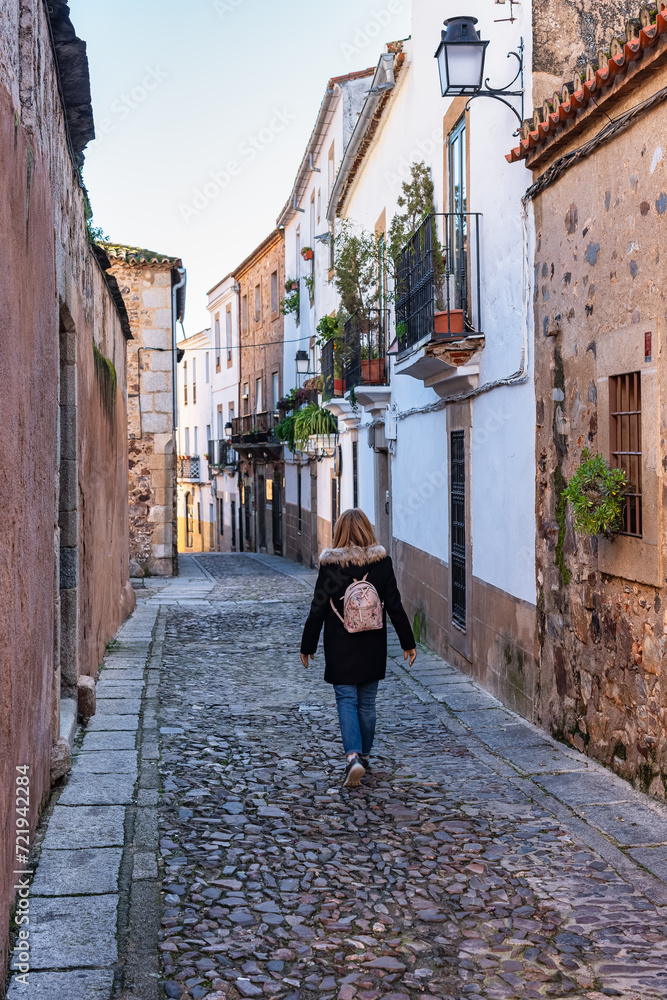 Tourist woman strolling quietly through the narrow streets of the city of Caceres.