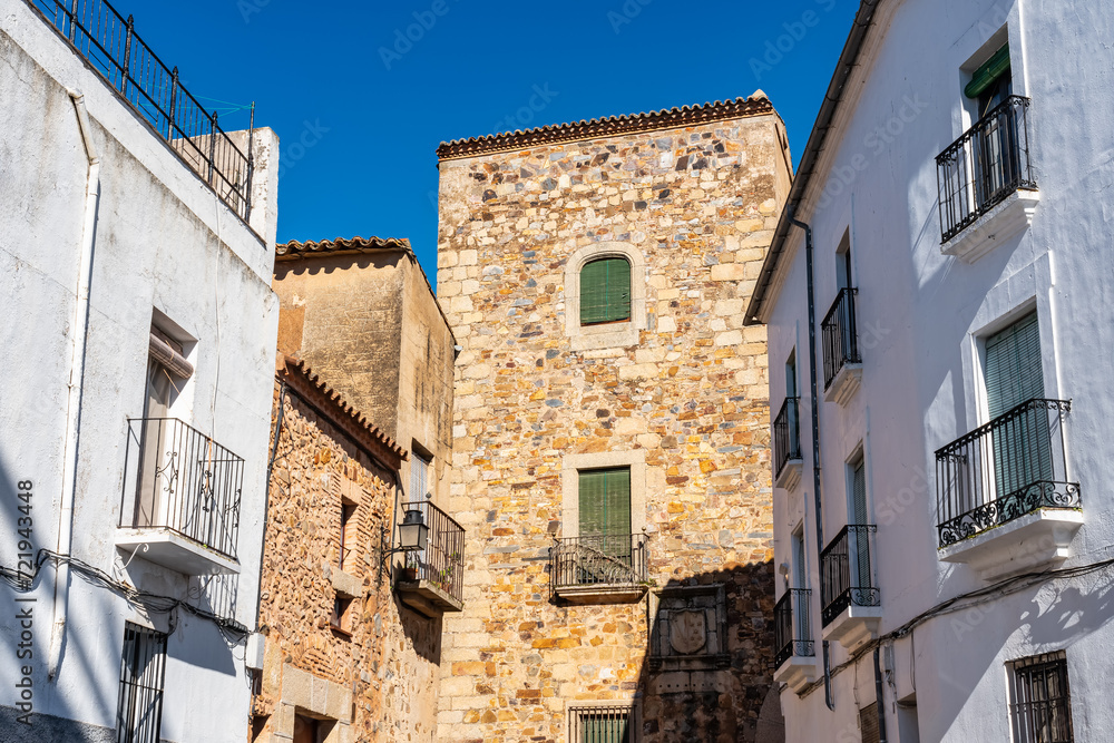Facades of white houses and medieval buildings in the city of Caceres, Spain.