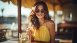 At the sea cafe, a young, stylish, and beautiful woman is enjoying pancakes, cocktails, and smoothies while dressed in a flirty resort-style outfit with sunglasses and a joyful face.