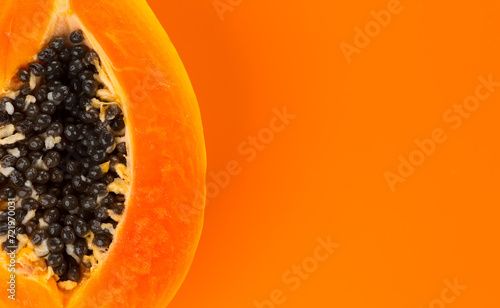 Papaya fruit on orange, yellow background. Halved fresh organic Papaya exotic fruit border design, close up. Top view. Copy space 