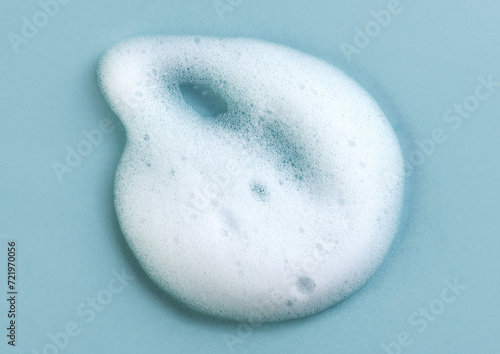 Foam smudge on blue background. Liquid soap bubbles, Froth bubbles backdrop. Cosmetics soap foam popping bubble. Soap sud macro structure close-up. Clean, cleaning, washing, laundry. Top view 