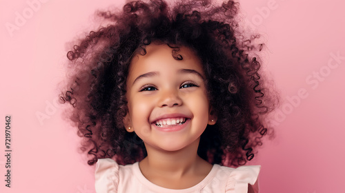 This adorable young girl exudes joy with her curly hair, captivating smile, and the vibrant pink background. © stocker