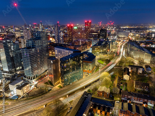 Aerial image of Manchester skyline early night showing new urban developments and trail of lights from the traffic.  © bardhok