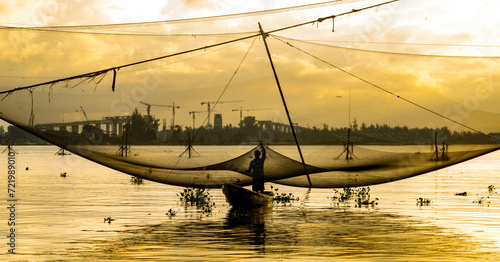 Photography Man standing in boat on water with fishing nets at sunrise in Hoi An, Vietnam