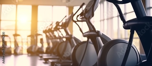 Elliptical in Modern gym interior with equipment. Row of training exercise bikes wheel detail photo