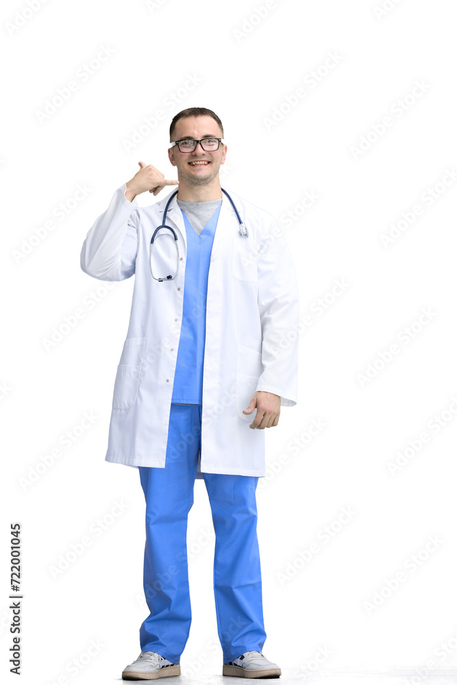 A male doctor, on a white background, in full height, shows a call sign A male doctor, on a white background, in full height, shows a call sign