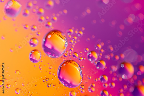 Purple and orange oily drops in water with colorful background close-up.