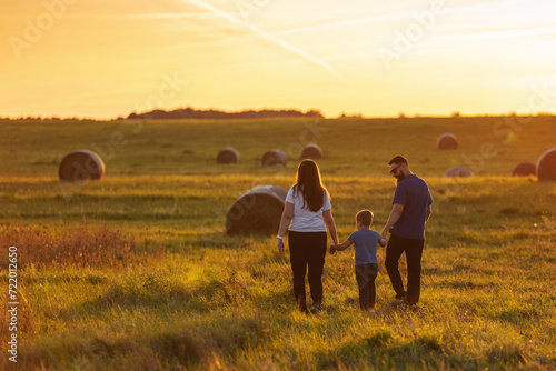 Mother  father and son are walking hand in hand through the wide fields of Lithuania in the evening light. A harmonious family during a walk in the fresh air