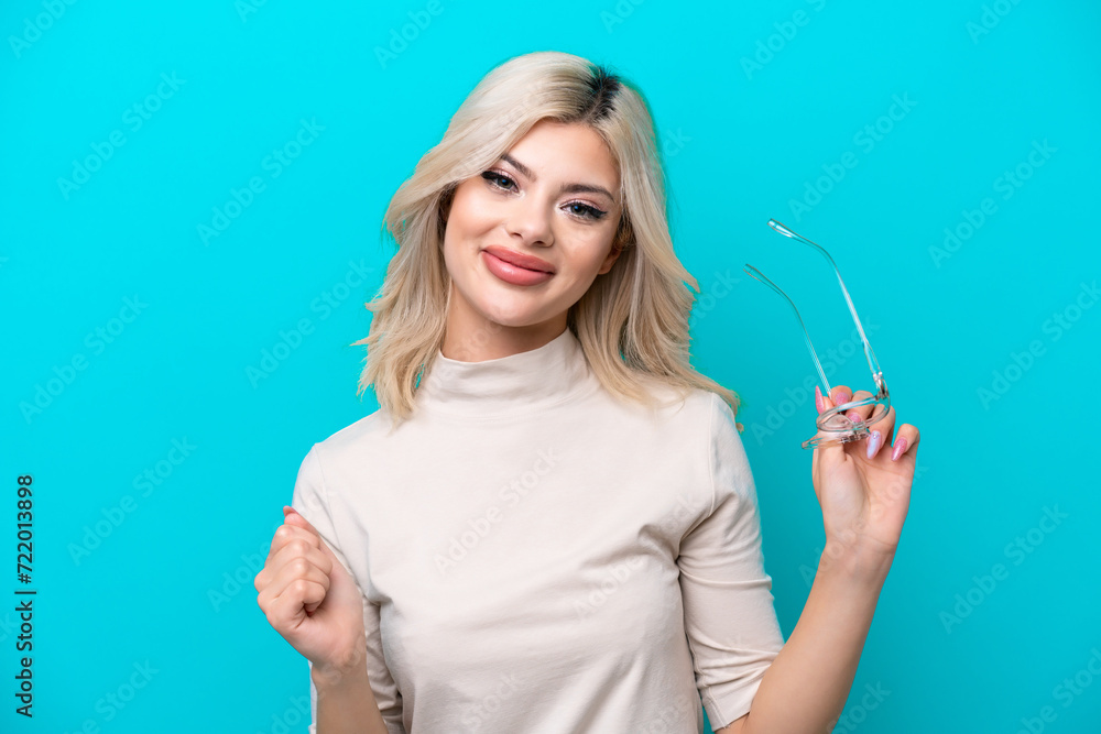 Obraz premium Young Russian woman isolated on blue background With glasses with happy expression