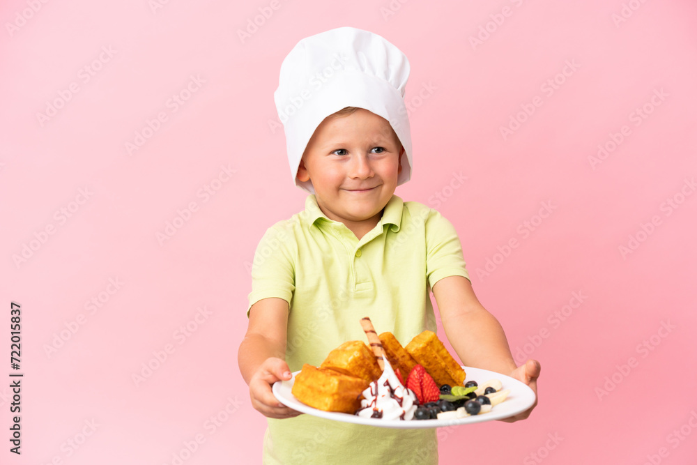Little Russian boy holding waffles over isolated background Little Russian boy holding waffles over isolated background