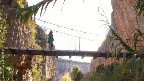 Woman walking on suspension bridge in tourist destination with huge cliffs, Chulilla. photo