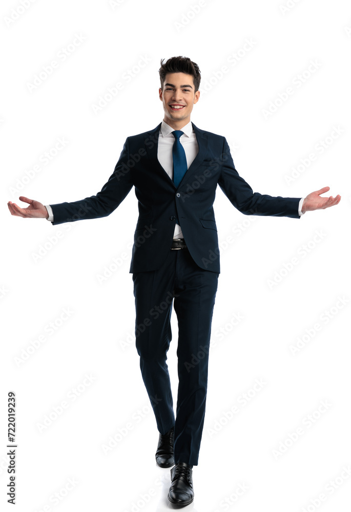 attractive young businessman in suit walking and presenting with opened arms attractive young businessman in suit walking and presenting with opened arms