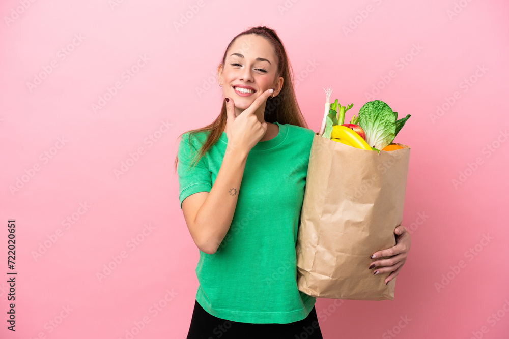 Young woman holding a grocery shopping bag happy and smiling Young woman holding a grocery shopping bag happy and smiling