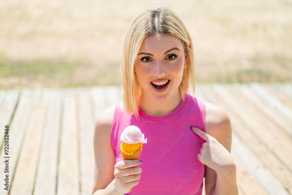 Young pretty blonde woman with a cornet ice cream at outdoors with surprise facial expression Young pretty blonde woman with a cornet ice cream at outdoors with surprise facial expression