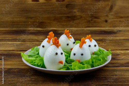 Funny easter breakfast with boiled eggs as chicks on wooden table © olyasolodenko
