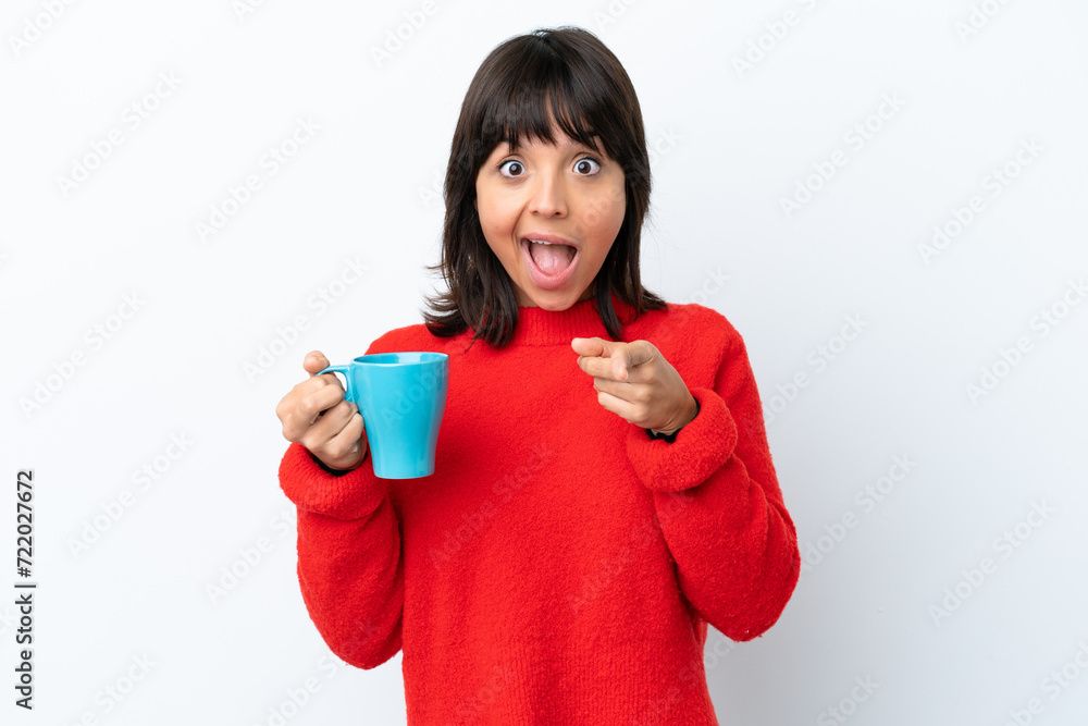 Young caucasian woman holding cup of coffee isolated on white background surprised and pointing front Young caucasian woman holding cup of coffee isolated on white background surprised and pointing front