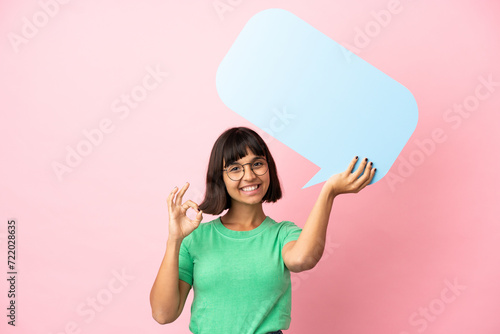 Youing woman holding an empty speech bubble and doing OK sign