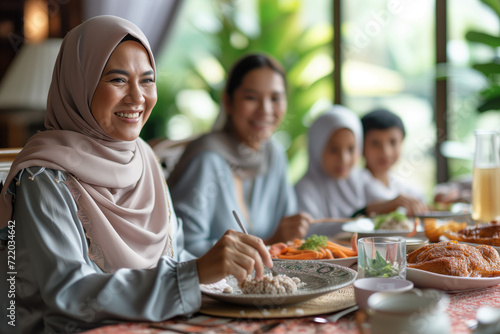 Happy Islamic woman enjoys with her family during meal at dining table