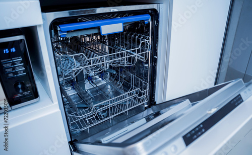 The white kitchen and opened dishwasher with clean dishes