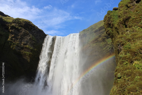 Iceland waterfall green grass and rainbow