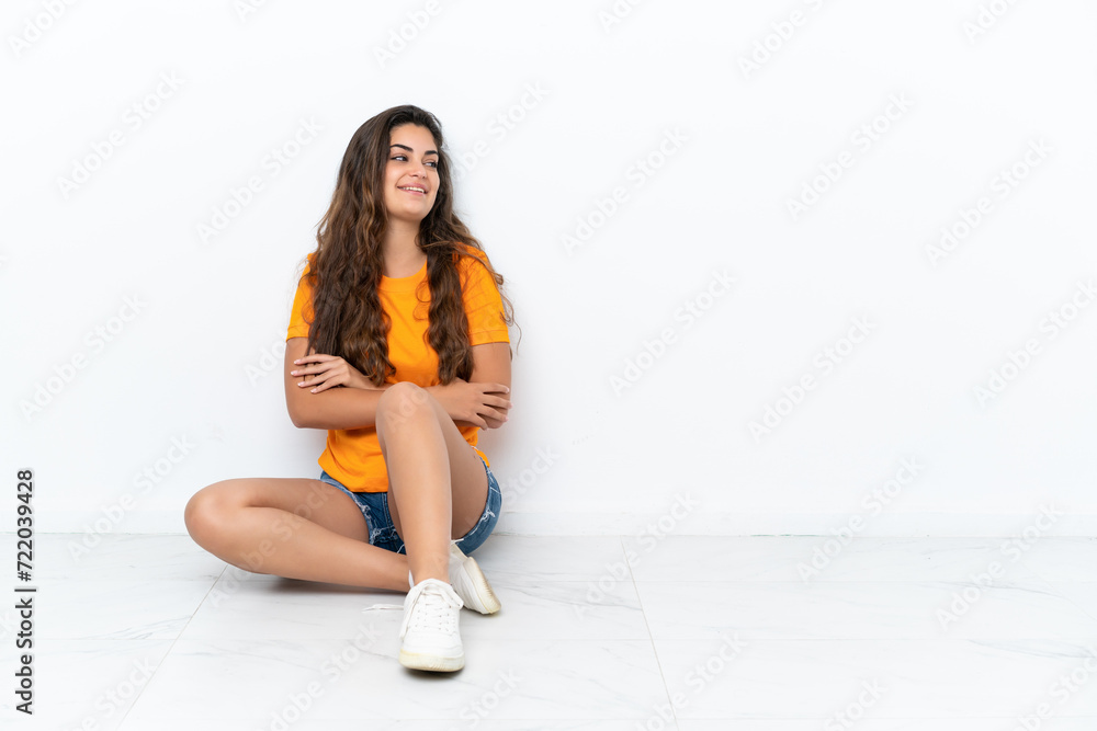 Young caucasian woman sitting on the floor isolated on white background happy and smiling Young caucasian woman sitting on the floor isolated on white background happy and smiling