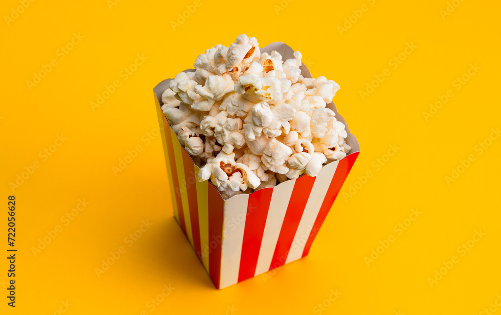 Popcorn in red and white striped paper box isolated on yellow background