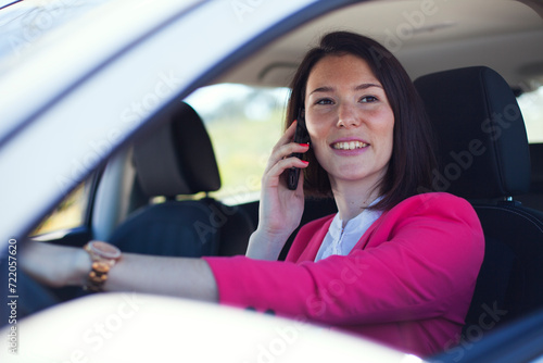 woman maneuvers her car, effortlessly multitasking as she engages in conversation on her mobile phone © Helder Almeida
