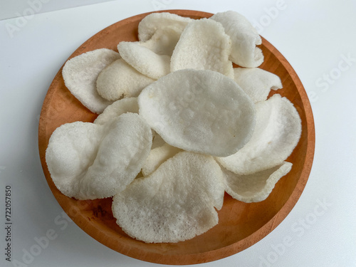 Kerupuk bawang putih, crackers made from tapioca flour and garlic, on wooden plated, isolated on white background