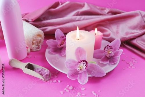 Spa still life with orchid flowers and candles on pink background, relaxation atmosphere, body care 