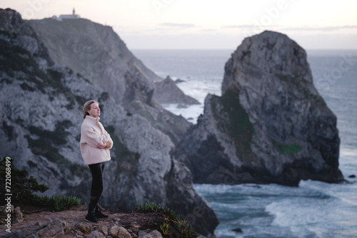 A woman looks at the ocean while standing on rocks, Atlantic coast, Sintra, Portugal. © De Visu