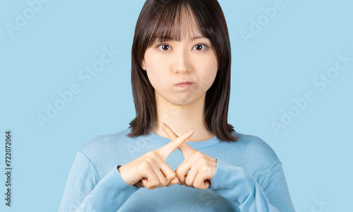 指でバツのポーズをする怒った表情の女性 photo