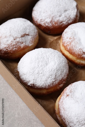 Delicious buns with powdered sugar on light grey table, closeup