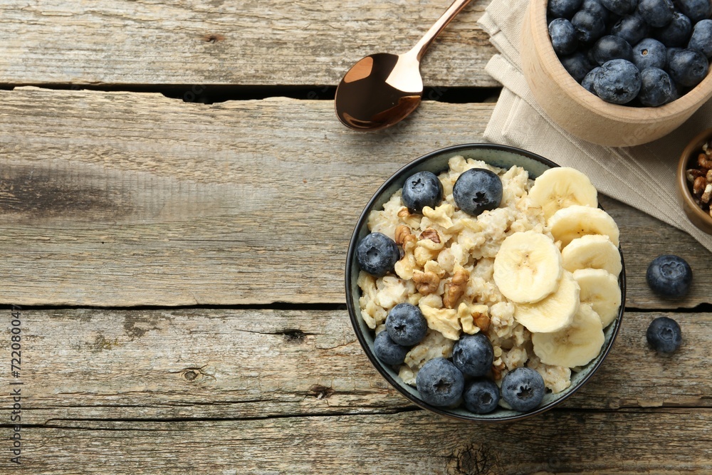 Tasty oatmeal with banana, blueberries and walnuts served in bowl on wooden table, flat lay. Space for text Tasty oatmeal with banana, blueberries and walnuts served in bowl on wooden table, flat lay. Space for text