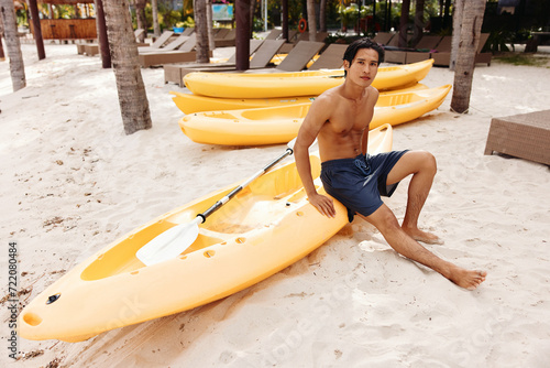 Serene Seascape: A Happy Asian Man Kayaking on a Tropical Beach, Enjoying a Healthy and Active Summer Vacation photo