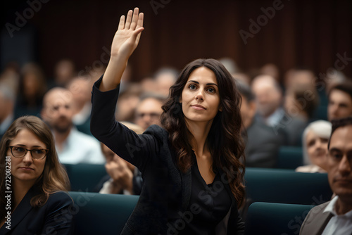 Active Engagement: Business Woman Participating in a Seminar, Eagerly Raising Her Hand to Pose a Question