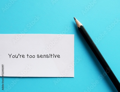 Card on blue background with handwriting YOU ARE TOO SENSITIVE - gaslighting way to accuse or emotional abuse others to question their beliefs or doubt their perception and become distressed photo