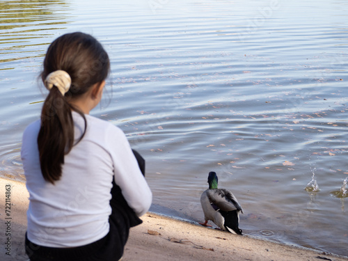 niña de espalda mirando un pato photo